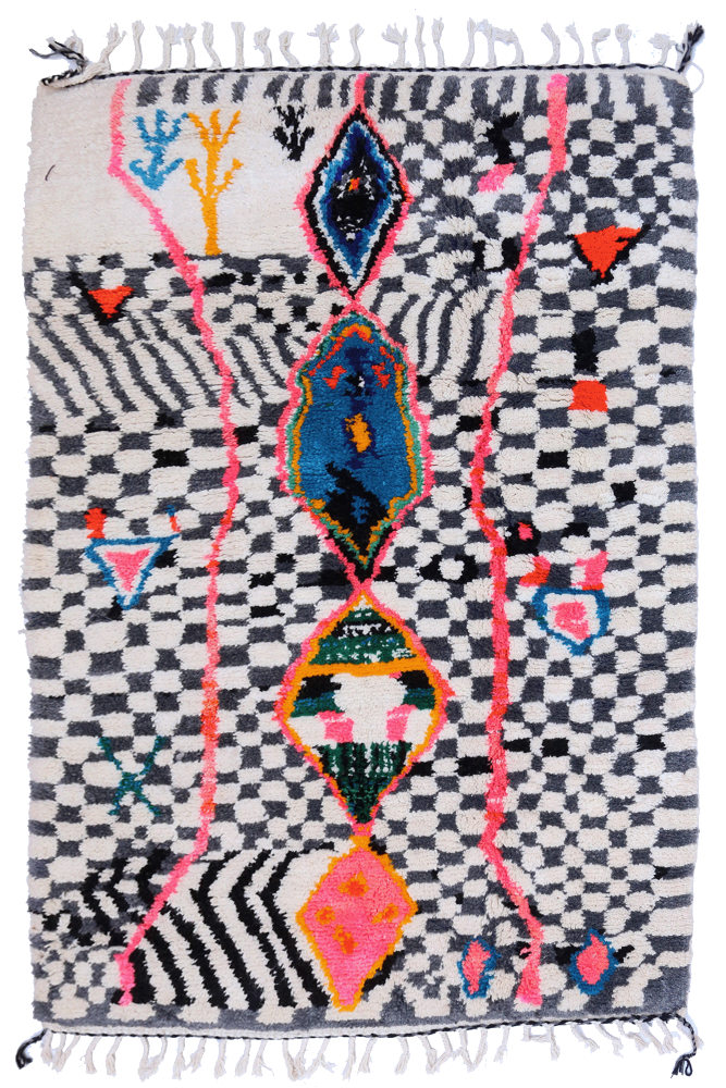 Tapis berbère aux motifs géométriques en noir et blanc avec des touches de couleurs vives comme le rose et le bleu.