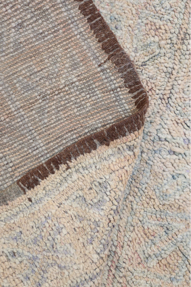 Tapis berbère aux motifs géométriques, dans des tons doux de beige et marron, alliant tradition et modernité.