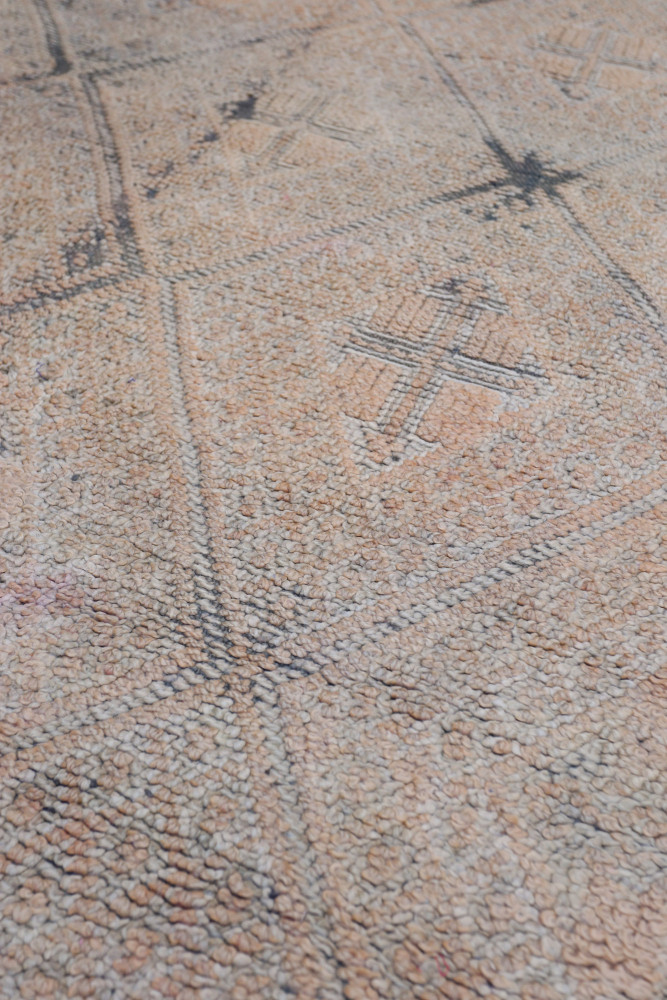 Tapis berbère aux motifs géométriques, dominé par des nuances de beige et des touches de noir.