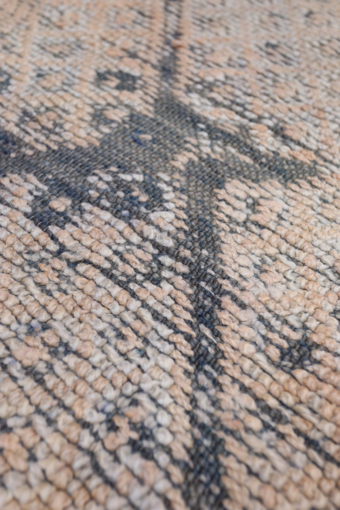 Tapis berbère aux motifs géométriques, dominé par des teintes beige et noir, ajoutant une touche artisanale élégante.
