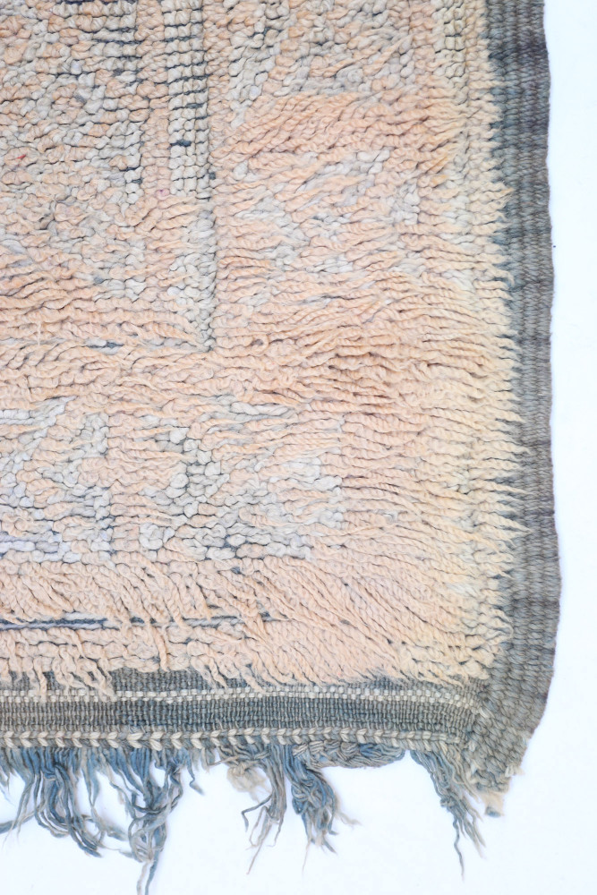 Tapis berbère en laine aux teintes douces de rose et bleu avec des motifs géométriques traditionnels.