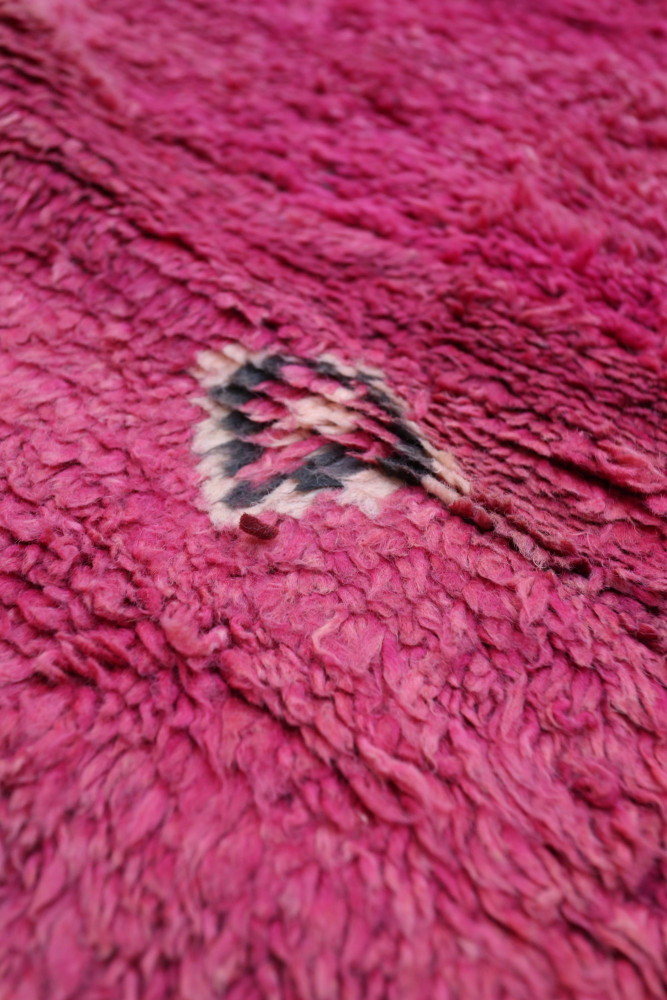 Tapis berbère en rose vif avec des motifs géométriques et une texture douce et moelleuse.