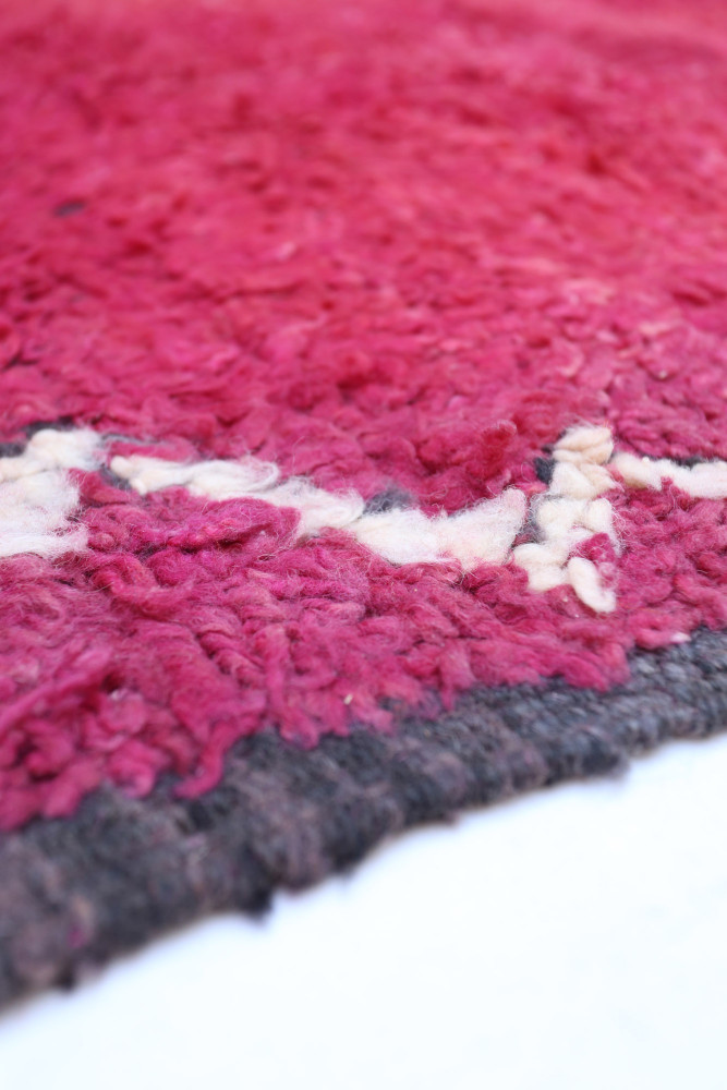 Tapis berbère en laine avec des teintes roses et crème, ornés de motifs géométriques élégants et modernes.
