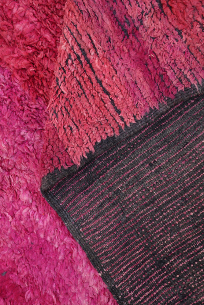 Tapis berbère en laine aux textures douces, dominé par des teintes rose et noir avec des motifs modernes.