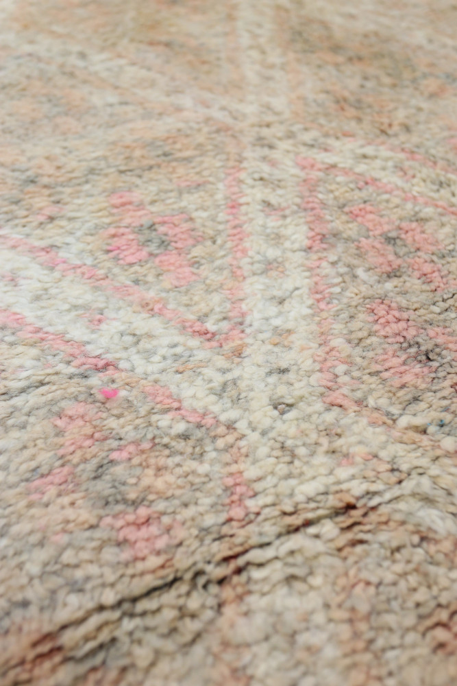 Tapis berbère aux motifs géométriques, teintes douces de beige et rose, ajoutant une touche chaleureuse à votre décoration.