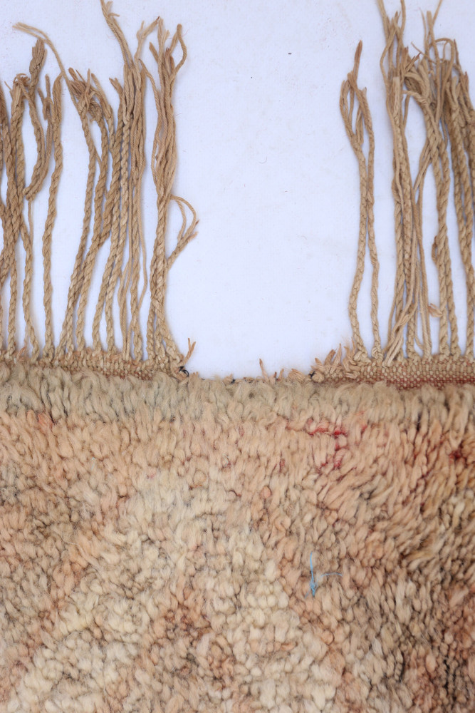 Tapis berbère beige avec motifs géométriques discrètes et franges naturelles, apportant une touche artisanale à votre décoration