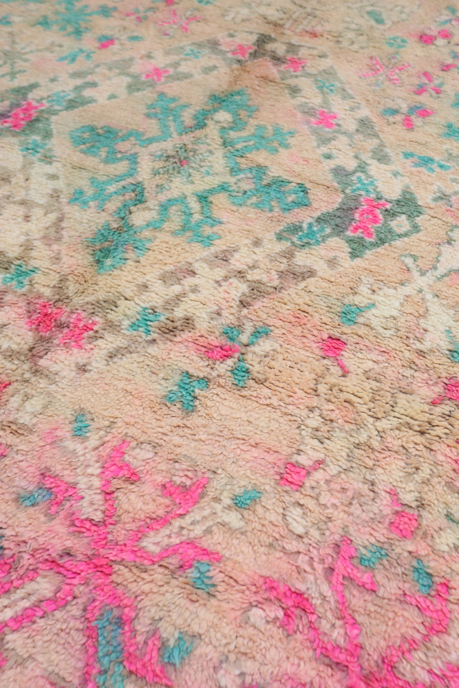 Tapis berbère aux motifs floraux colorés avec des tons de rose, turquoise et beige, parfait pour une décoration moderne.
