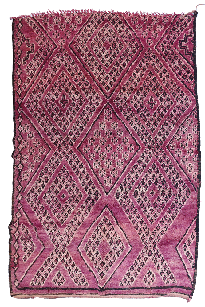 Tapis berbère aux motifs géométriques, dominant des nuances de rose et de violet, créant une ambiance chaleureuse et moderne.