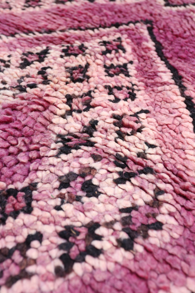 Tapis berbère aux teintes roses et noires avec des motifs géométriques délicats.