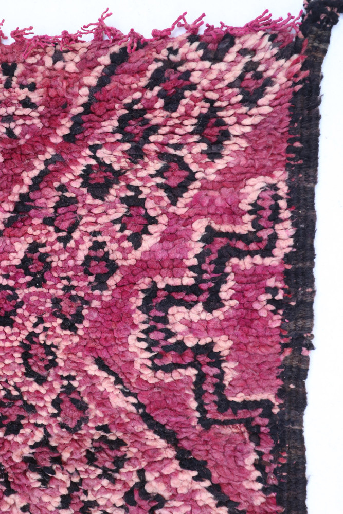 Tapis berbère en rose et noir avec des motifs géométriques distincts, ajoutant une touche artisanale et chaleureuse.