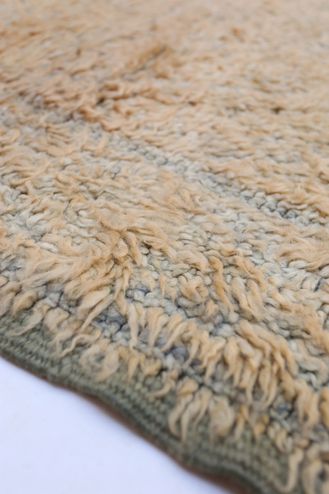 Tapis berbère en laine aux teintes beige et vert, avec un motif texturé et nuancé caractéristique.