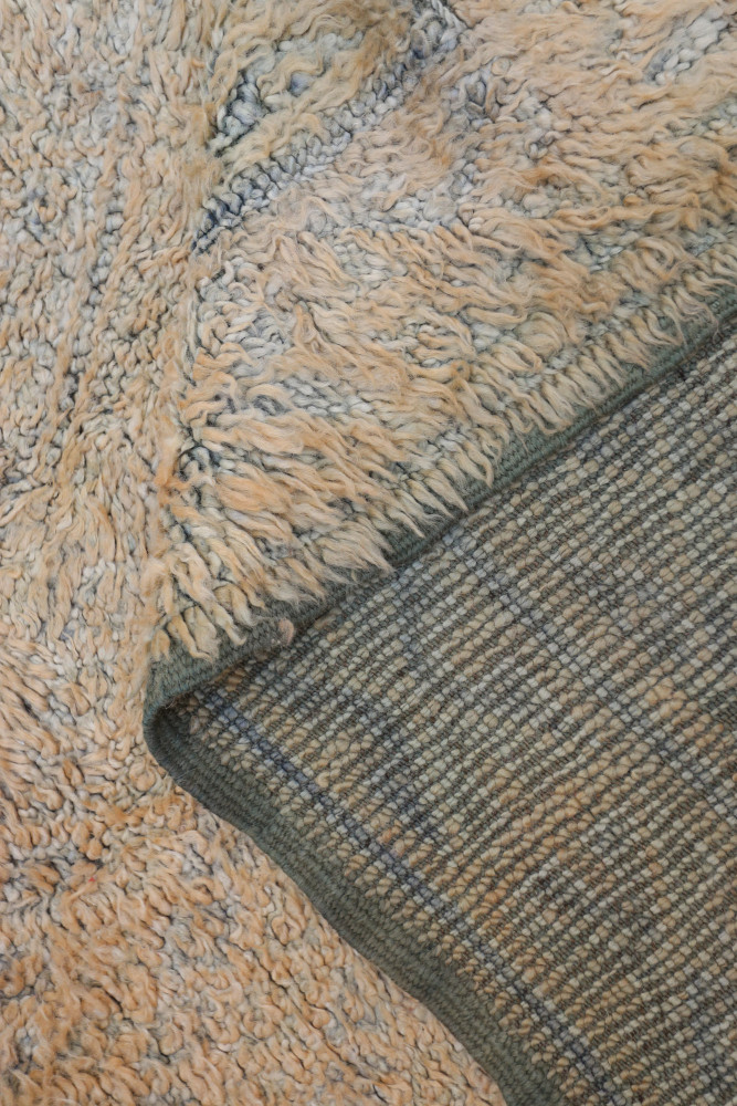 Tapis berbère aux tons beige et gris, avec des motifs texturés et une finition douce.