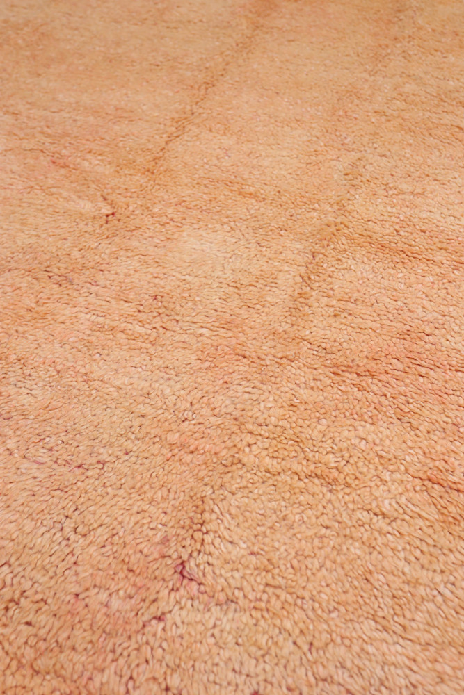 Tapis berbère en tons doux de rose et beige, tissé à la main avec un design texturé subtil.