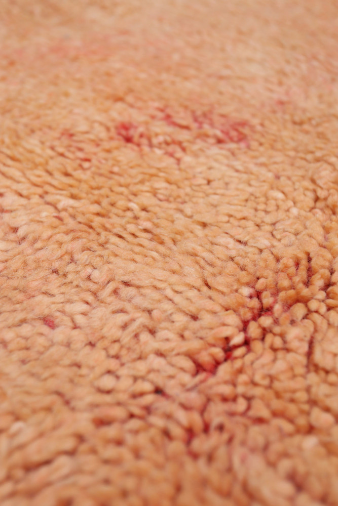 Tapis berbère en laine, couleur pêche douce avec des motifs naturels subtils et une texture douillette.