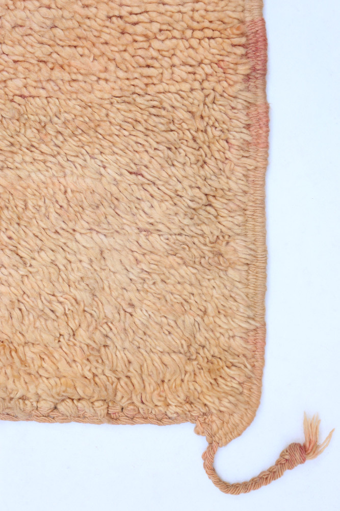 Tapis berbère en laine avec des tons beiges et des motifs texturés, ajoutant une touche chaleureuse à votre intérieur.