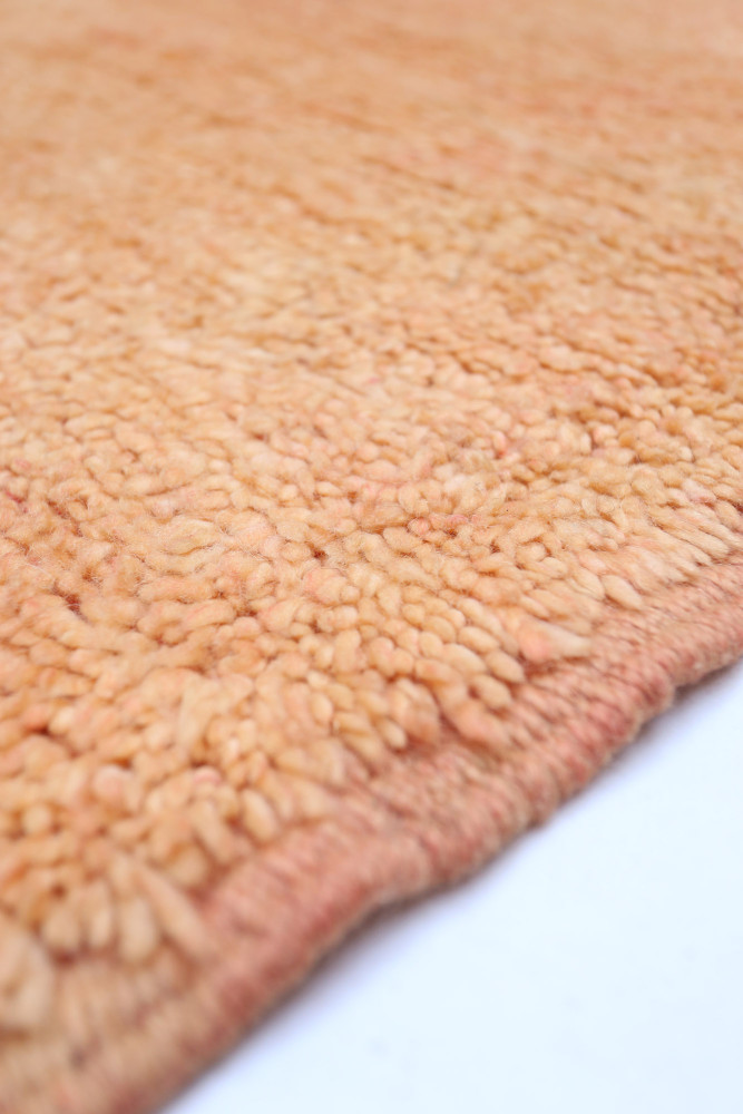Tapis berbère doux aux teintes pêche avec un motif texturé et artisanal, parfait pour ajouter une touche chaleureuse à votre int