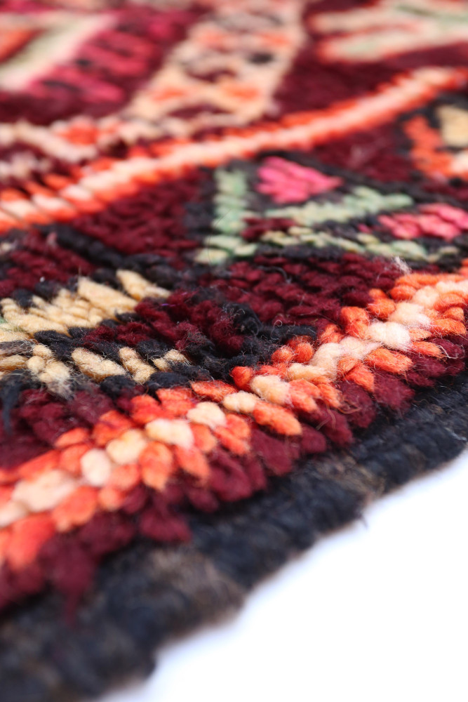 Tapis berbère riche en couleurs rouge, noir et orange avec des motifs géométriques et floraux traditionnels.