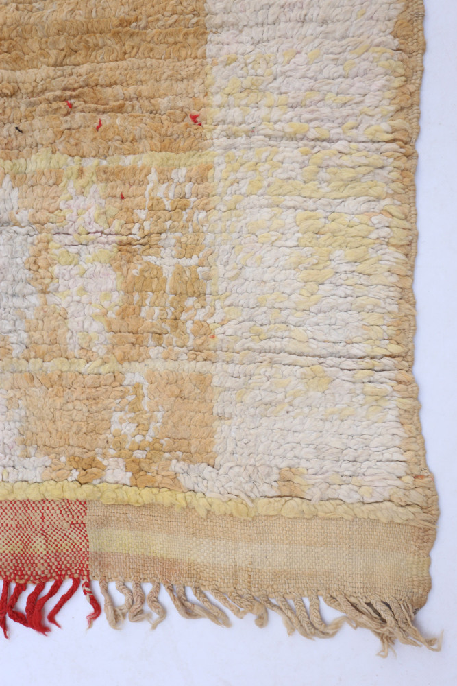 Tapis berbère aux teintes jaunes et blanches avec des motifs texturés et des touches de rouge, idéal pour un intérieur chaleureu