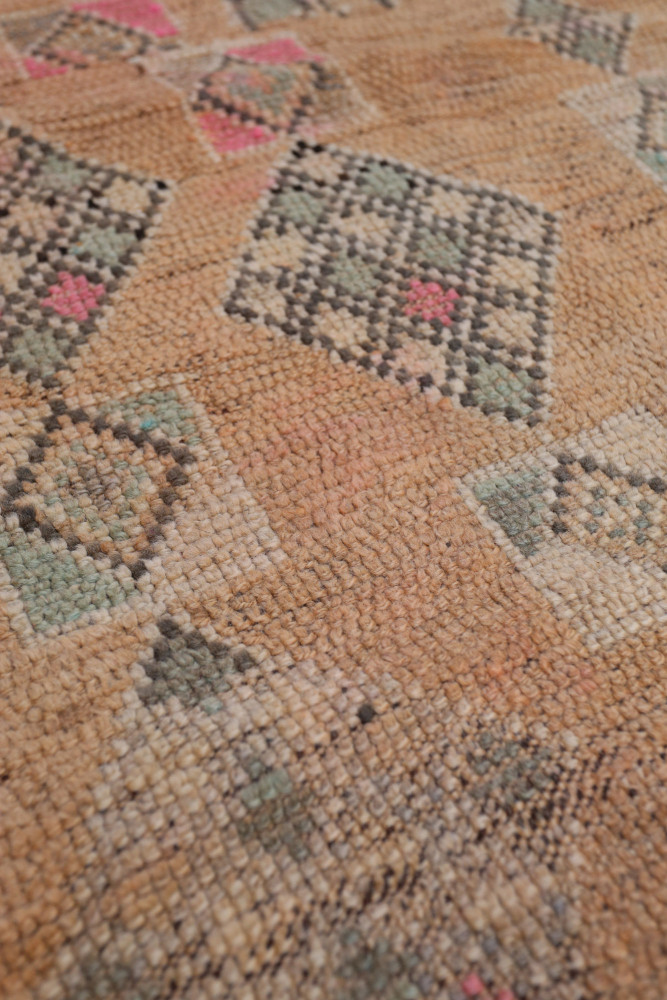 Tapis berbère en jute aux motifs géométriques en rose, vert et noir sur fond beige.