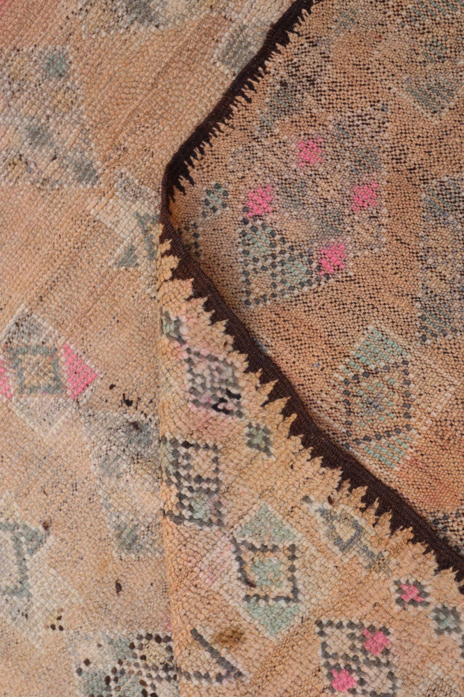 Tapis berbère en jute aux teintes naturelles, motifs géométriques en bleu, rose et crème.