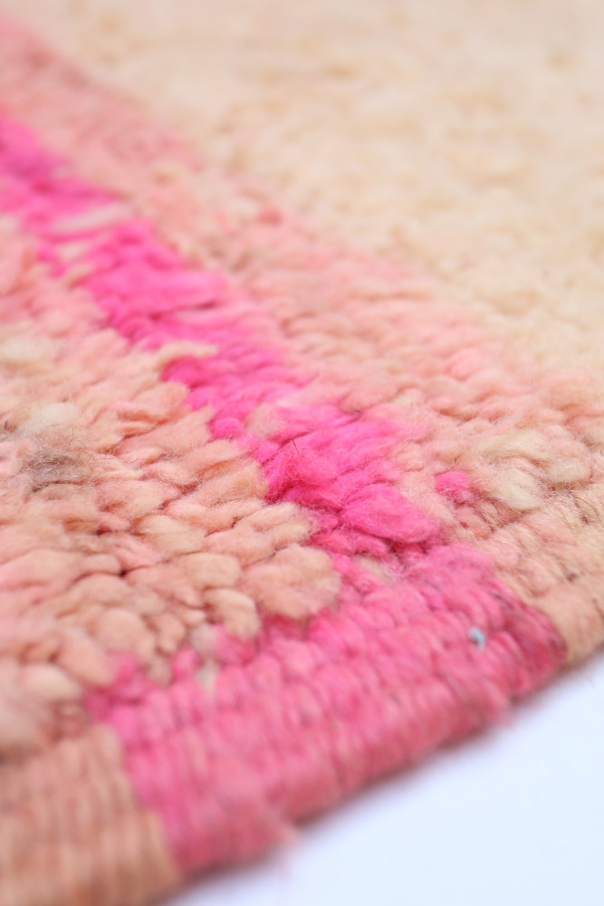 Tapis berbère aux couleurs douces, mélange de nuances rose et beige avec un motif simple et texturé.