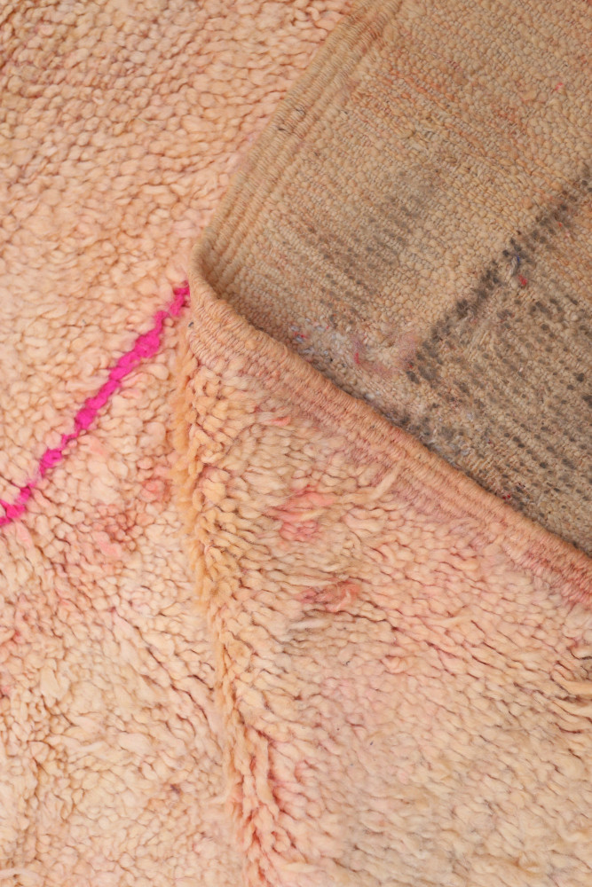 Tapis berbère aux teintes pastel, motifs géométriques subtils et détails en rose, évoquant une ambiance chaleureuse et authentiq