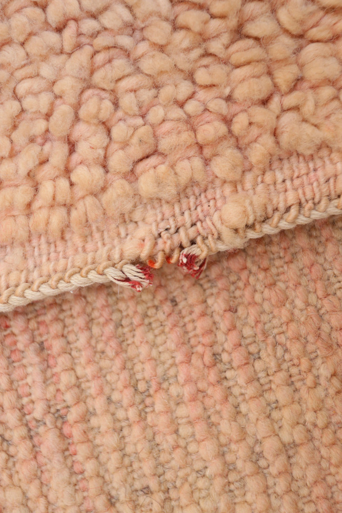 Tapis berbère en laine, couleur rose pâle avec des motifs doux et texturés, parfait pour une ambiance chaleureuse.