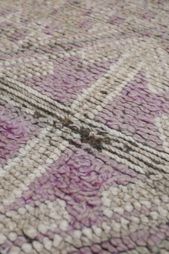 Tapis berbère vintage aux teintes douces de violet et beige avec motifs géométriques raffinés.