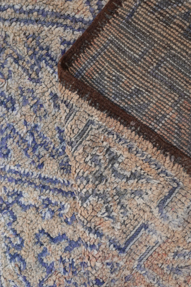 Tapis berbère aux motifs géométriques, dominé par des nuances de beige et de bleu, ajoutant une touche artisanale.