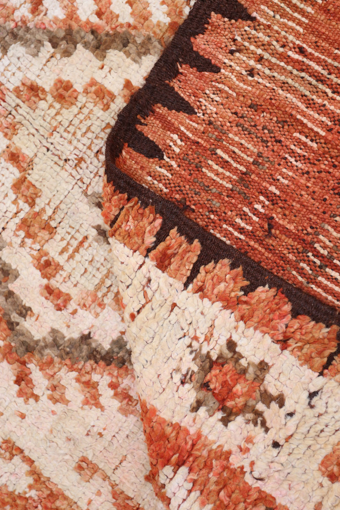 Tapis berbère aux motifs géométriques en orange, beige et brun, réchauffant votre intérieur avec style.