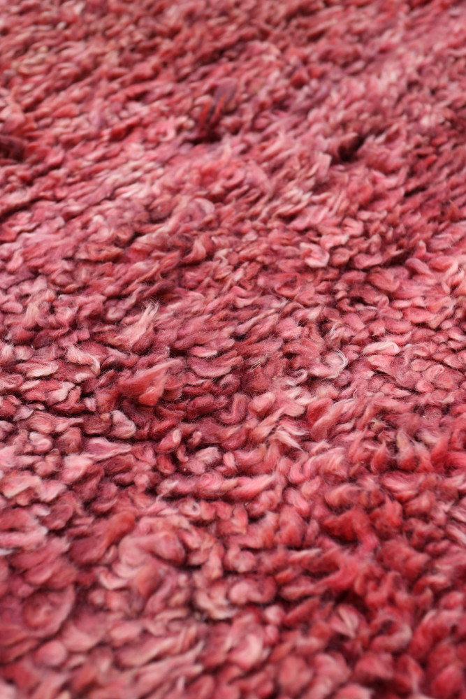 Tapis berbère en laine, teintes rouges doux et motifs texturés, ajoutant chaleur et âme à votre intérieur.