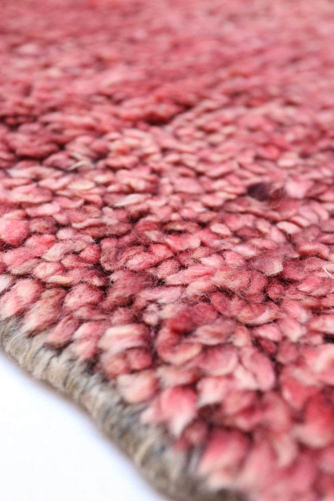 Tapis berbère coloré en dégradé de rose avec des motifs texturés et doux.