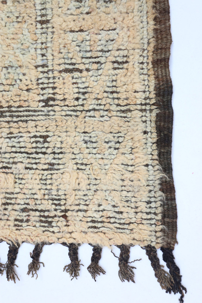 Tapis berbère aux motifs géométriques avec des nuances de beige et de noir, idéal pour un intérieur trendy.