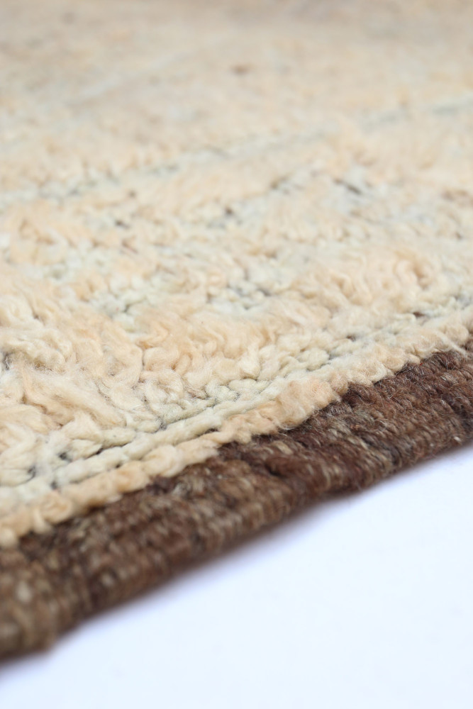Tapis berbère à motifs géométriques, aux teintes crème et marron, apportant une touche artisanale et chaleureuse.