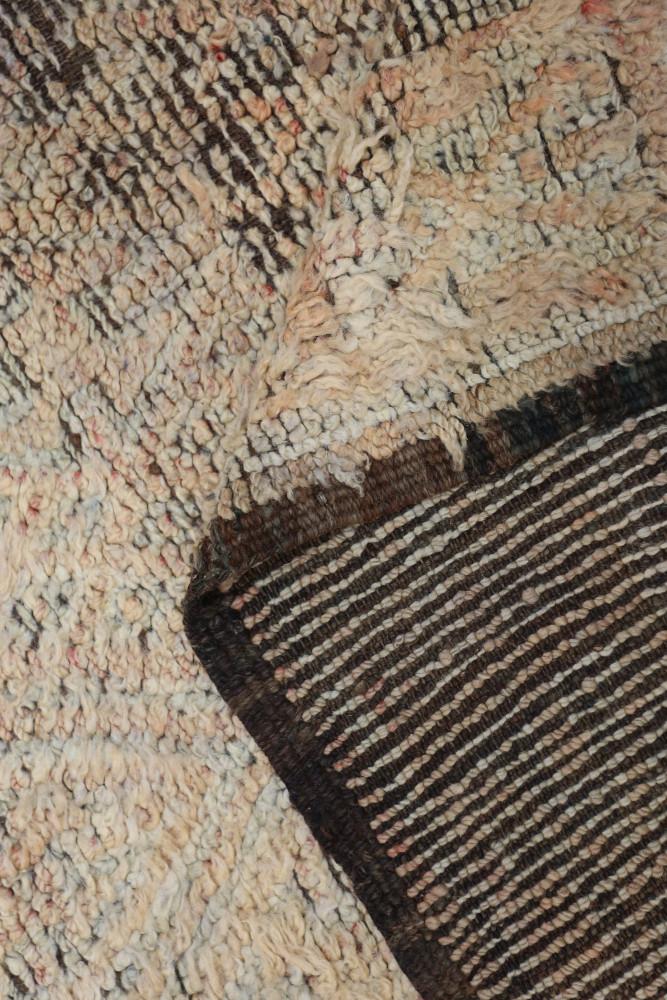 Tapis berbère à motifs géométriques avec des teintes crème, brunes et des touches de couleur vintage.