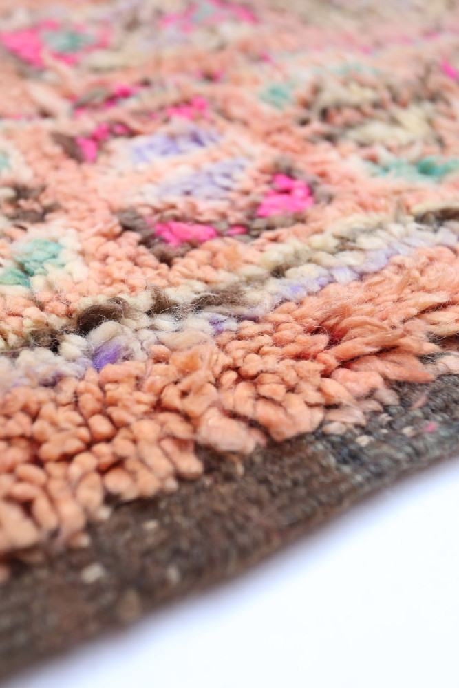 Tapis berbère aux teintes chaudes, motifs géométriques colorés avec des nuances de rose, orange et bleu pastel.