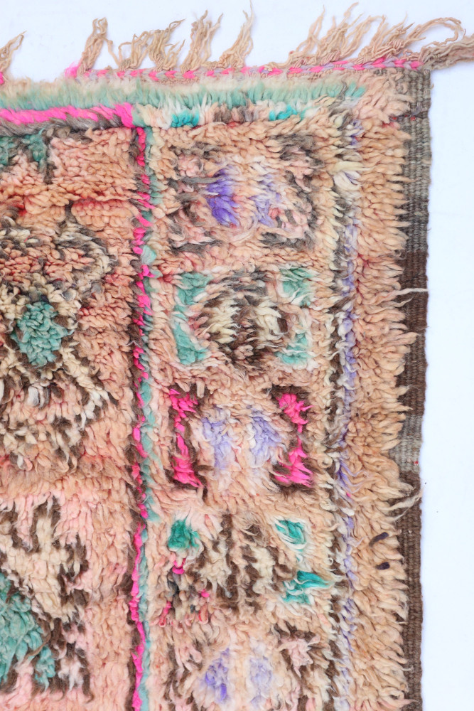 Tapis berbère aux motifs géométriques, couleurs terre et accents rose, ajoutant une touche artisanale unique.