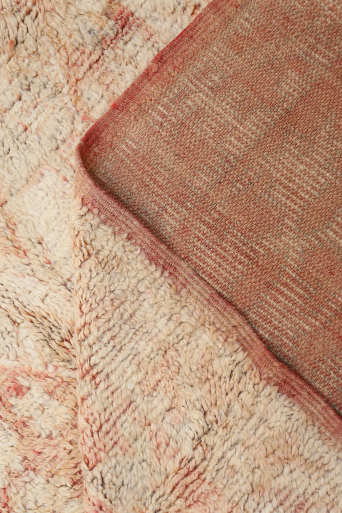 Tapis berbère aux motifs abstraits, dans des teintes de beige et rose, apportant chaleur et authenticité à votre intérieur.