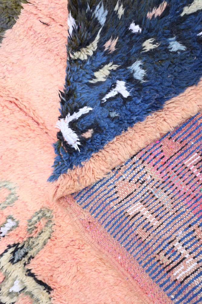 Tapis berbère aux motifs géométriques, dominé par des teintes rose, bleu et crème dans un style contemporain.