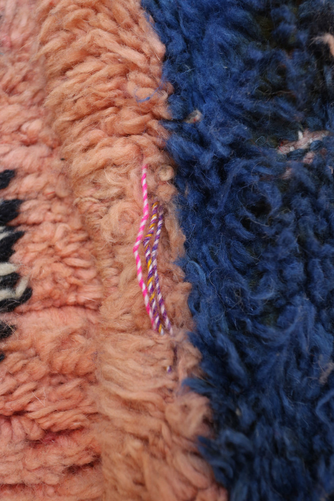 Tapis berbère multicolore avec des motifs géométriques en rose, bleu et noir, idéal pour une décoration moderne.