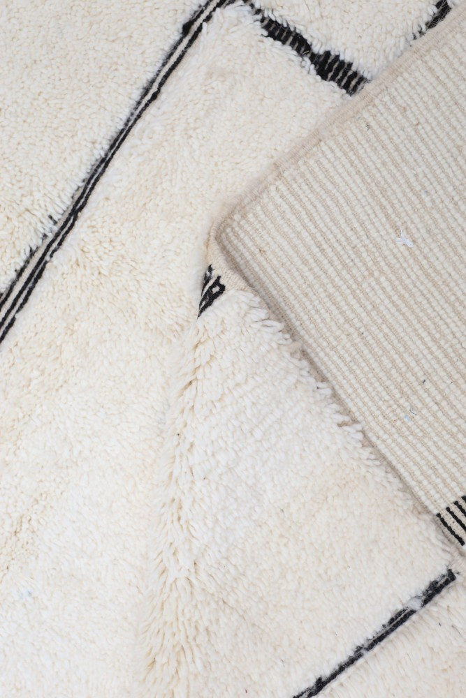 Tapis berbère blanc crème avec des motifs géométriques noirs, offrant un style moderne et contemporain.