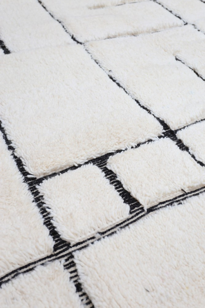 Tapis berbère au design géométrique, avec des nuances de blanc et noir, ornés de motifs de carrés.