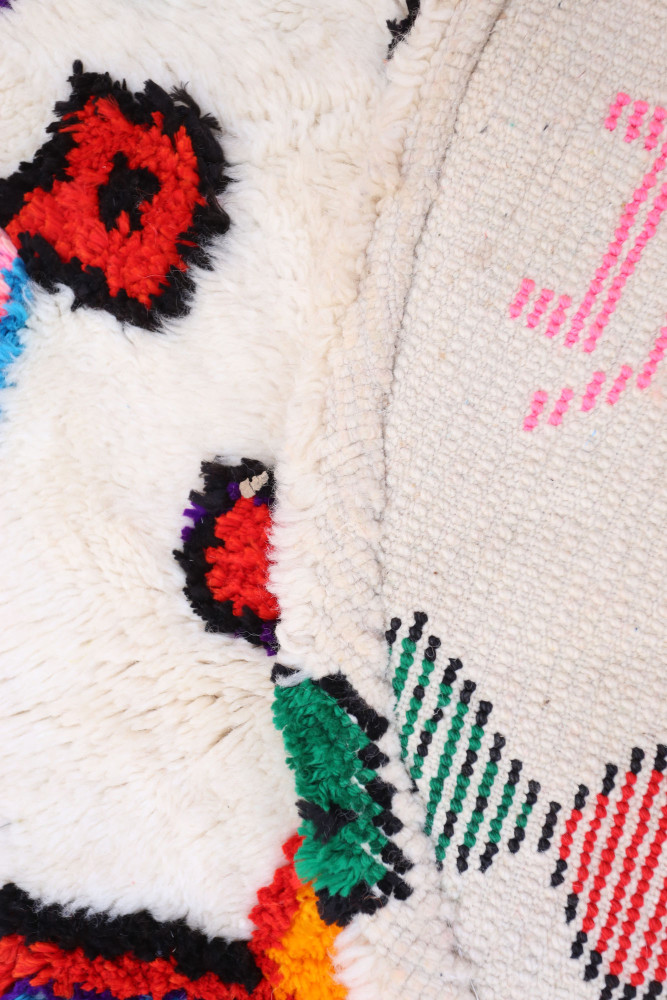 Tapis berbère en laine avec motifs colorés, dominé par des rouges, noirs et verts dans un style contemporain.