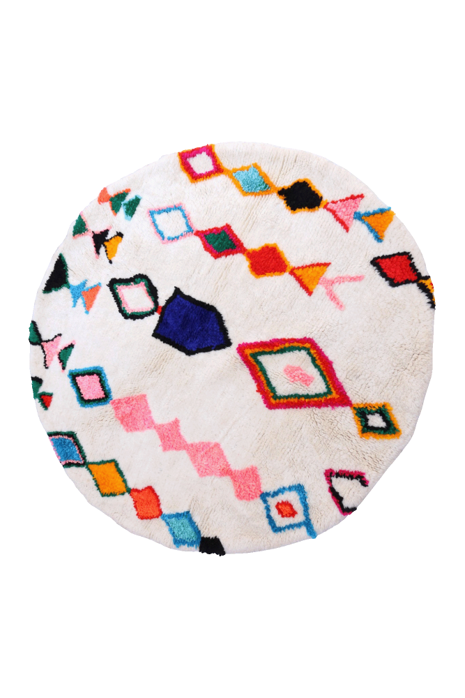 Tapis berbère rond aux motifs géométriques colorés, dominé par des teintes blanches, roses et bleues.