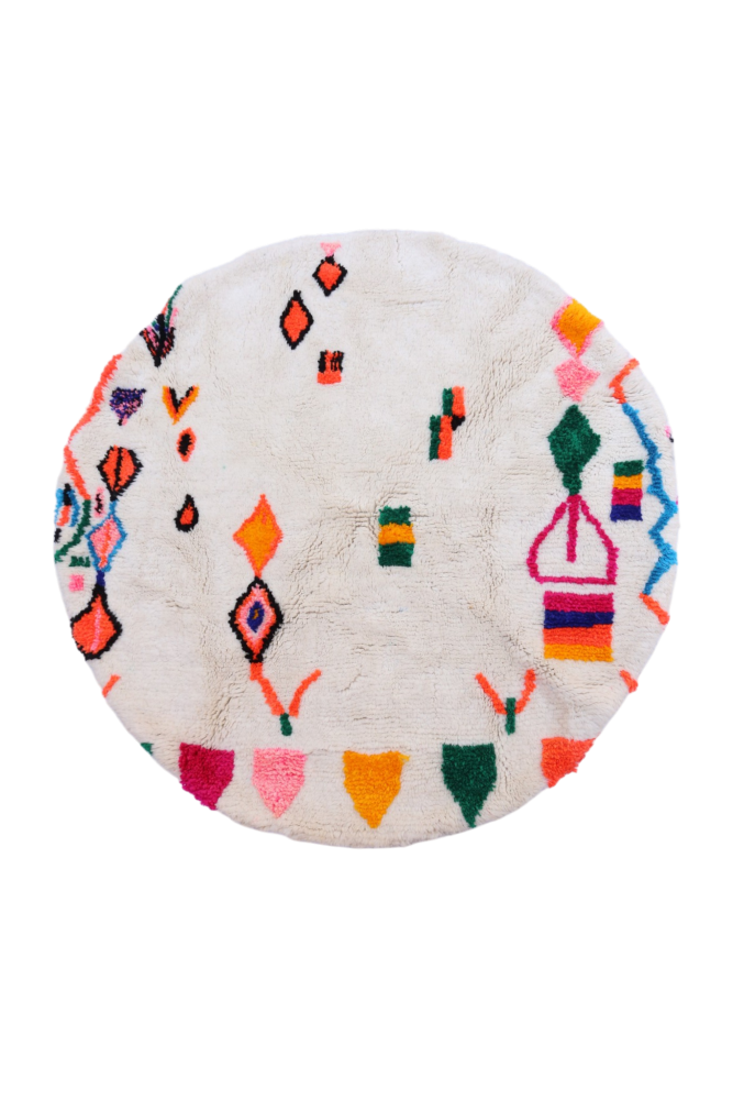 Tapis berbère rond avec motifs colorés en rose, orange, bleu et vert sur fond crème, ajoutant une touche bohème.
