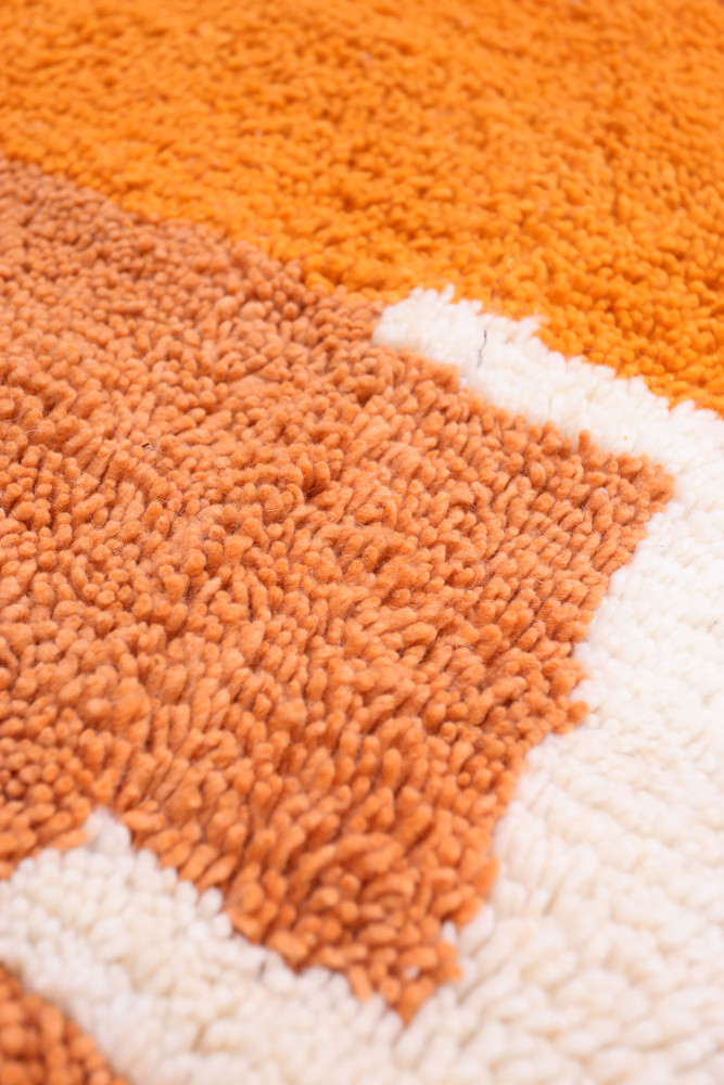 Tapis berbère aux couleurs orange et crème, avec des motifs en textures douces et modernes.