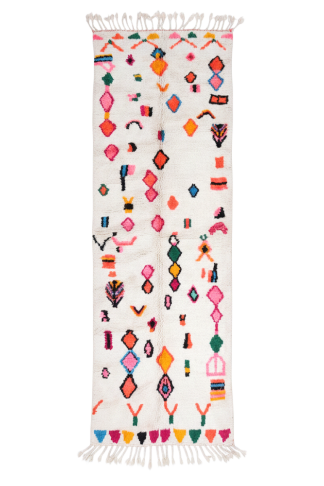 Tapis berbère aux motifs géométriques colorés sur fond blanc, avec des tons vifs de rose, bleu et vert.