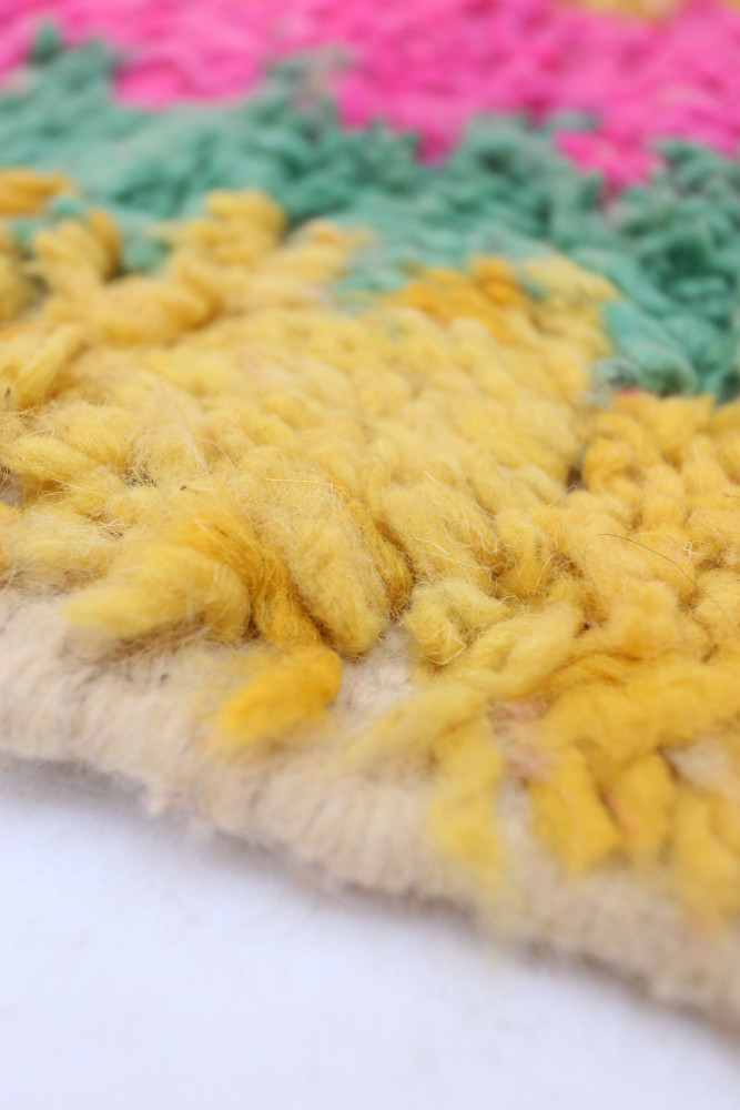 Tapis berbère aux couleurs vives, motifs géométriques en jaune, rose et vert, offrant une touche artisanale unique.