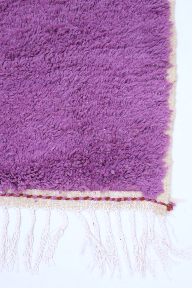 Tapis berbère en laine avec des nuances de violet et des motifs délicats sur les bords, parfait pour un salon moderne.
