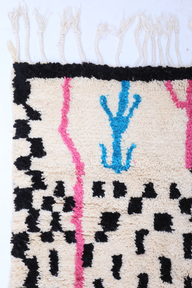 Tapis berbère en laine, aux motifs géométriques noir, bleu turquoise et rose sur fond crème, pour un style moderne et coloré.